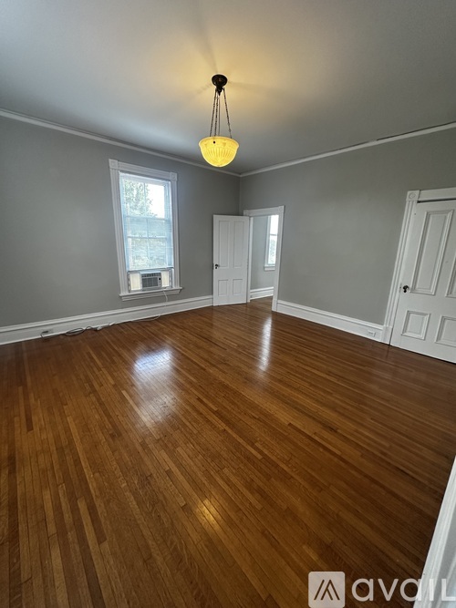 A room with wooden flooring and a hanging light fixture.