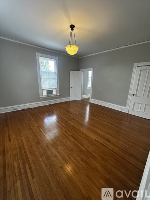 A room with wooden flooring and a hanging light fixture.