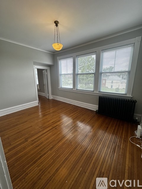 A room with wooden floors and a window with blinds.