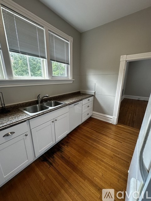A kitchen with white cabinets and a wooden floor.