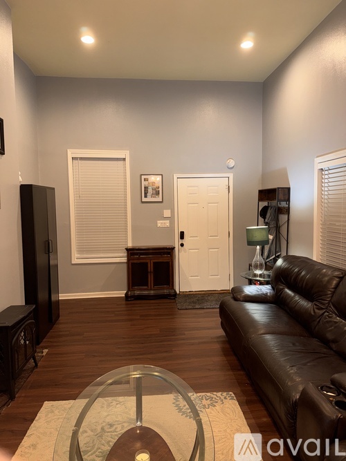 A living room with a brown leather couch and a glass coffee table.