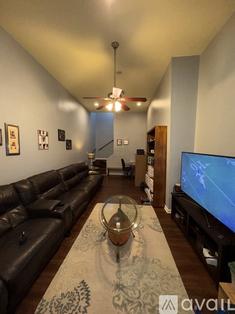 A living room with a large leather sofa and a television on the right side.