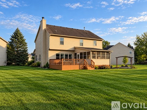 A house with a brown roof and a deck in the front yard.