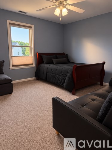 A bedroom with a large bed and a window overlooking a house.