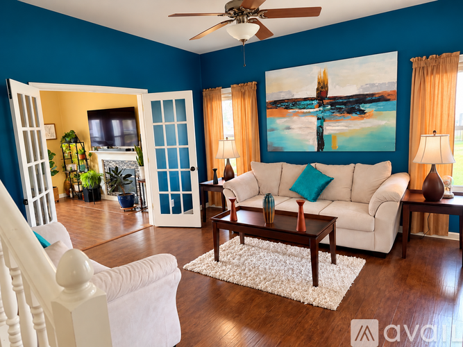 A living room with a white couch and a painting on the wall.
