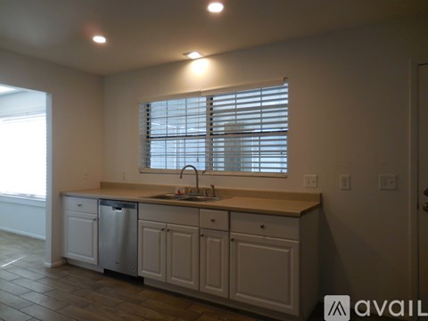 A kitchen with a sink, dishwasher and window.