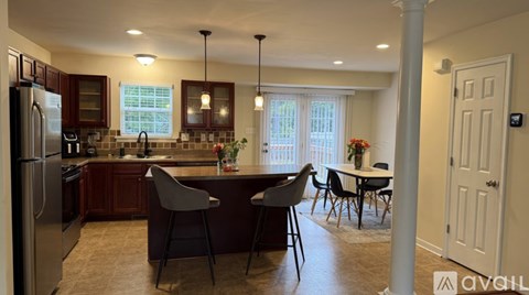 A kitchen with a refrigerator, sink, and dining table with chairs.
