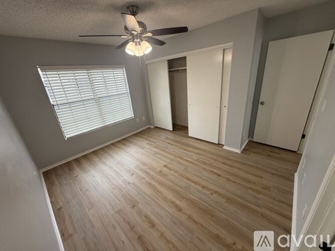 A room with a ceiling fan and wooden flooring.