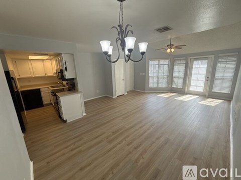A spacious living room with hardwood floors and a chandelier.