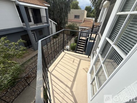 A balcony with a metal railing and steps leading to a building.