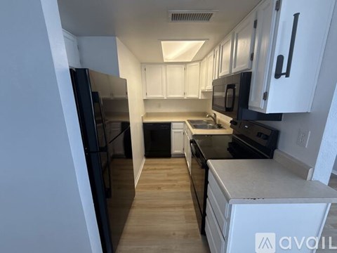 A kitchen with white cabinets and black appliances.
