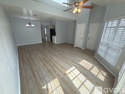 A spacious room with wooden flooring and a ceiling fan.