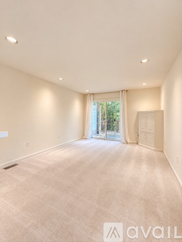 A spacious room with a carpeted floor and a sliding glass door leading to a balcony.