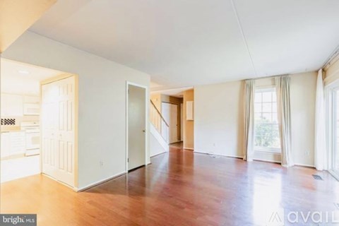 A spacious room with wooden floors and white walls.