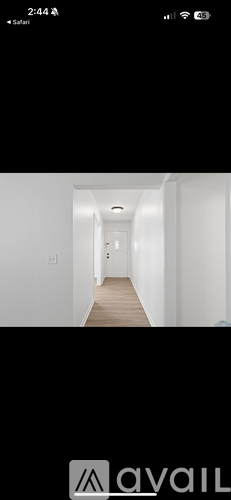 A long, narrow hallway with white walls and a wooden floor.