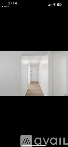 A long, narrow hallway with white walls and a wooden floor.