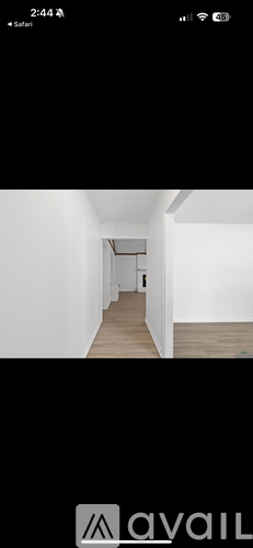 A long, narrow hallway with white walls and wooden flooring.