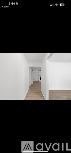 A long, narrow hallway with white walls and wooden flooring.