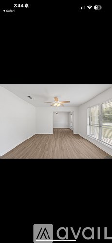 A room with a ceiling fan and wooden flooring.