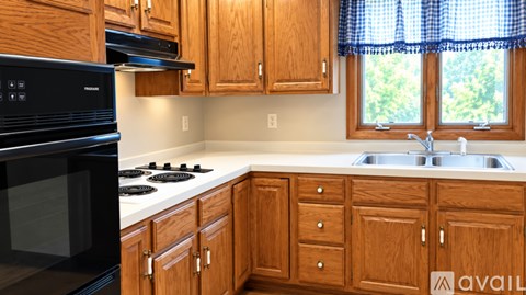 A kitchen with wooden cabinets and a black microwave.