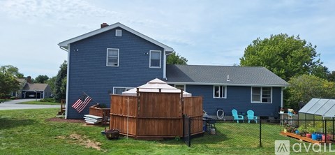 A blue house with a wooden fence and a hot tub in the yard.
