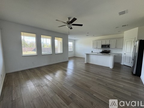 A spacious room with wooden flooring and a ceiling fan.