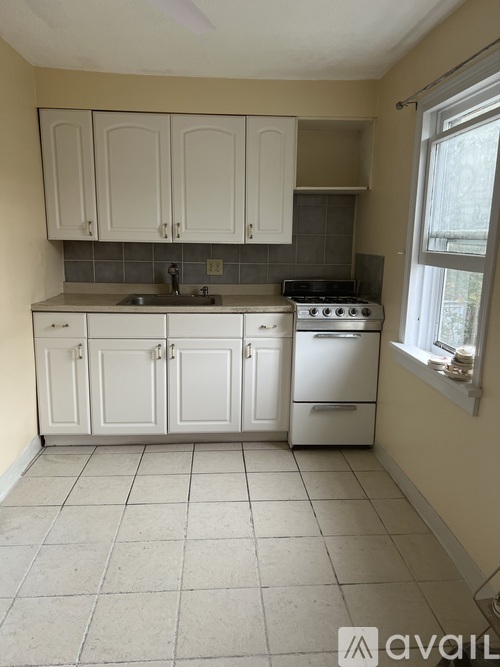 A kitchen with white cabinets and a tiled floor.