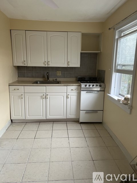 A kitchen with white cabinets and a tiled floor.