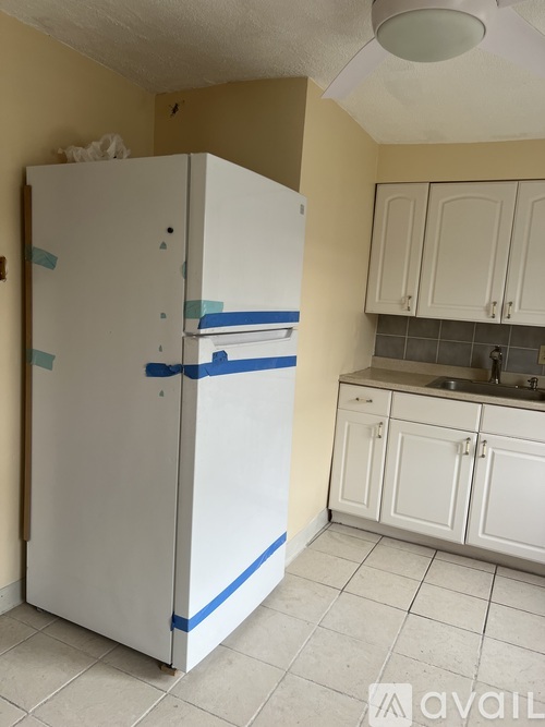 A white refrigerator with blue tape on it.
