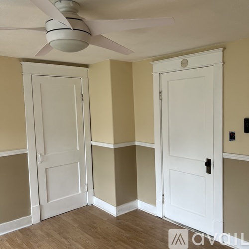 A room with a ceiling fan and two doors.