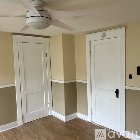 A room with a ceiling fan and two doors.