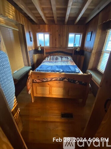 A bedroom with a bed in the middle and a window on the right.