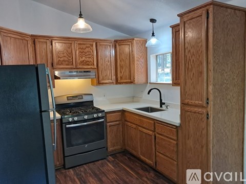 A kitchen with wooden cabinets and a black refrigerator.