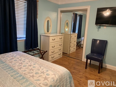 A bedroom with a bed, chair, and a dresser with mirrors.