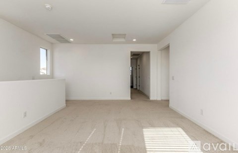 A spacious, empty room with a carpeted floor and white walls.
