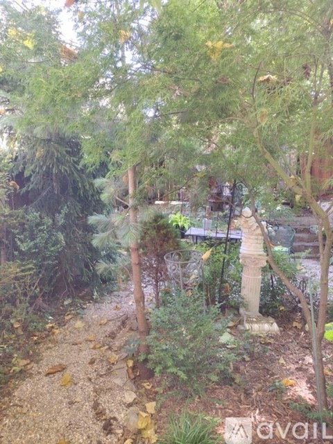A garden with a stone pillar and trees.