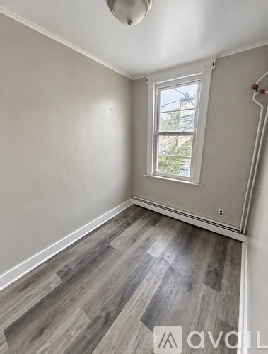 A room with a window and wooden flooring.