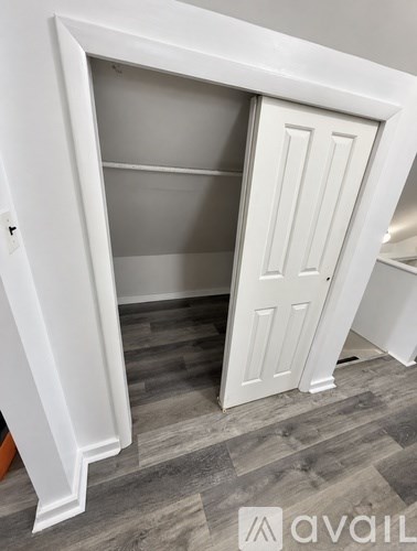 A white wardrobe with a door open and a shelf inside.