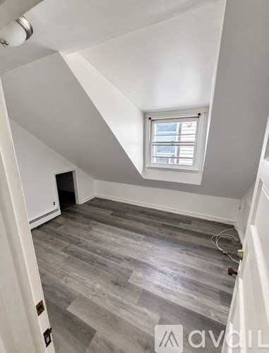 A room with a window and wooden flooring.