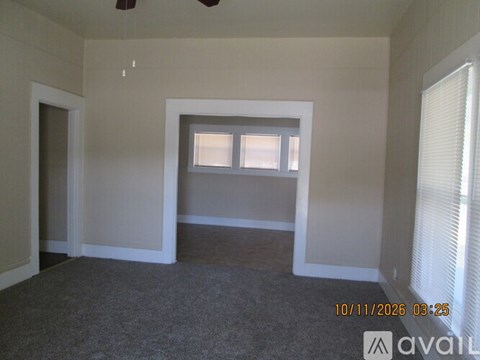A room with a window and a carpeted floor.