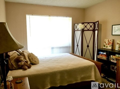 A bedroom with a bed, a chair, a dresser, and a window.
