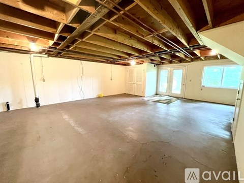 A spacious room with wooden ceiling and exposed beams.