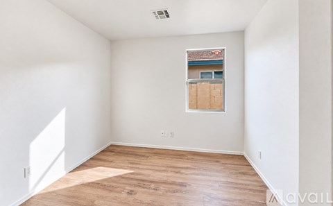 A room with wooden flooring and a window showing a view of a building.