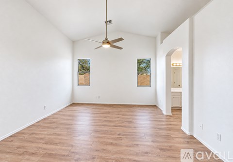 A spacious room with a ceiling fan and two paintings on the wall.