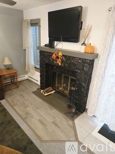 A living room with a fireplace and a television mounted above it.
