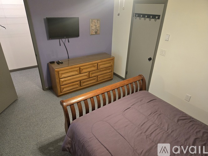 A bedroom with a bed, dresser, and a television.