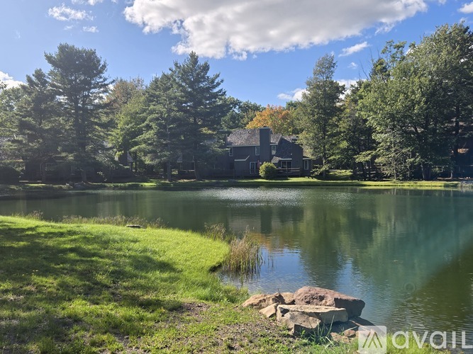 A serene lake surrounded by trees and a house in the distance.