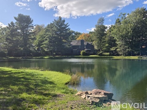 A serene lake surrounded by trees and a house in the distance.