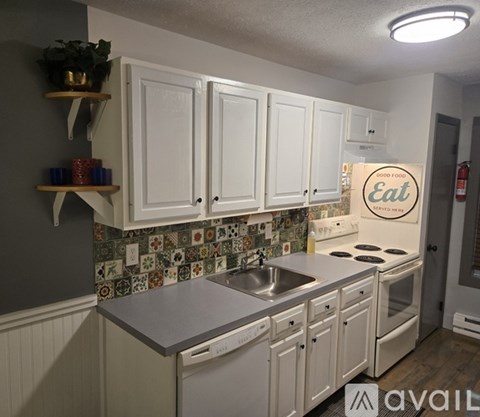 A kitchen with white cabinets and a tile backsplash.