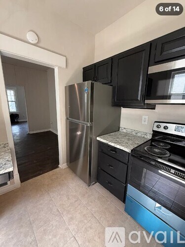 A kitchen with black cabinets and a stainless steel refrigerator.